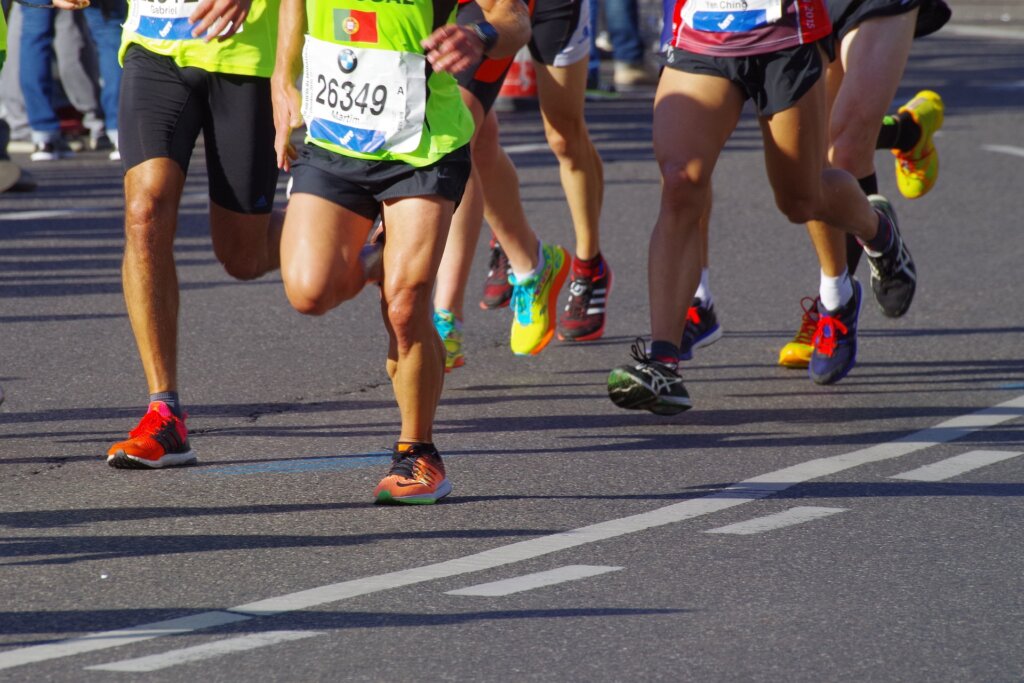 legs of marathon runners on asphalt