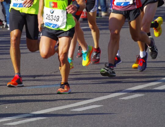 legs of marathon runners on asphalt