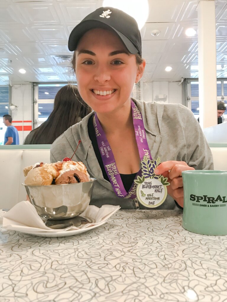 woman sitting with a vegan ice cream sunday, holding a running medal