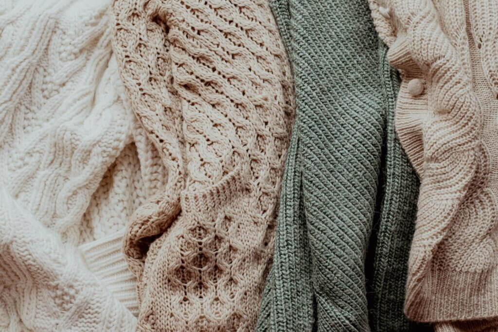Neutral-colored knit sweaters lie side by side