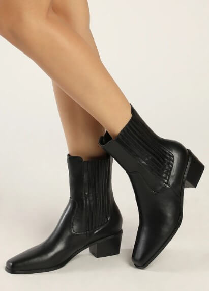 A model wears a pair of low-cut black boots