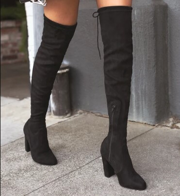 A model wears a pair of black knee-high vegan suede boots