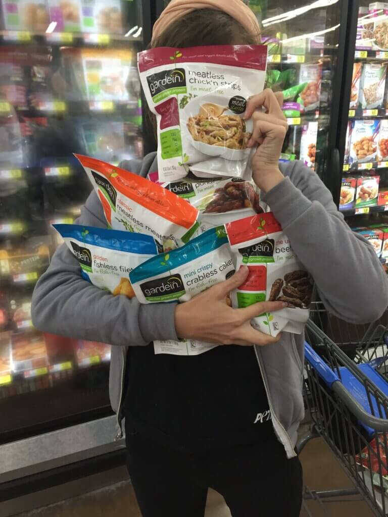 Person stands in a grocery store holding frozen vegan options