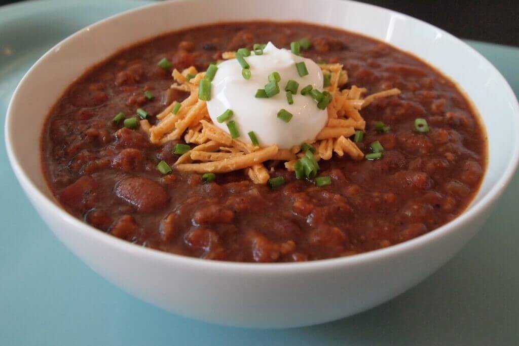 Vegan chili topped with vegan cheese and sour cream