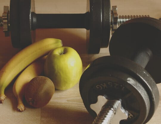 Weights on a table next to fruit
