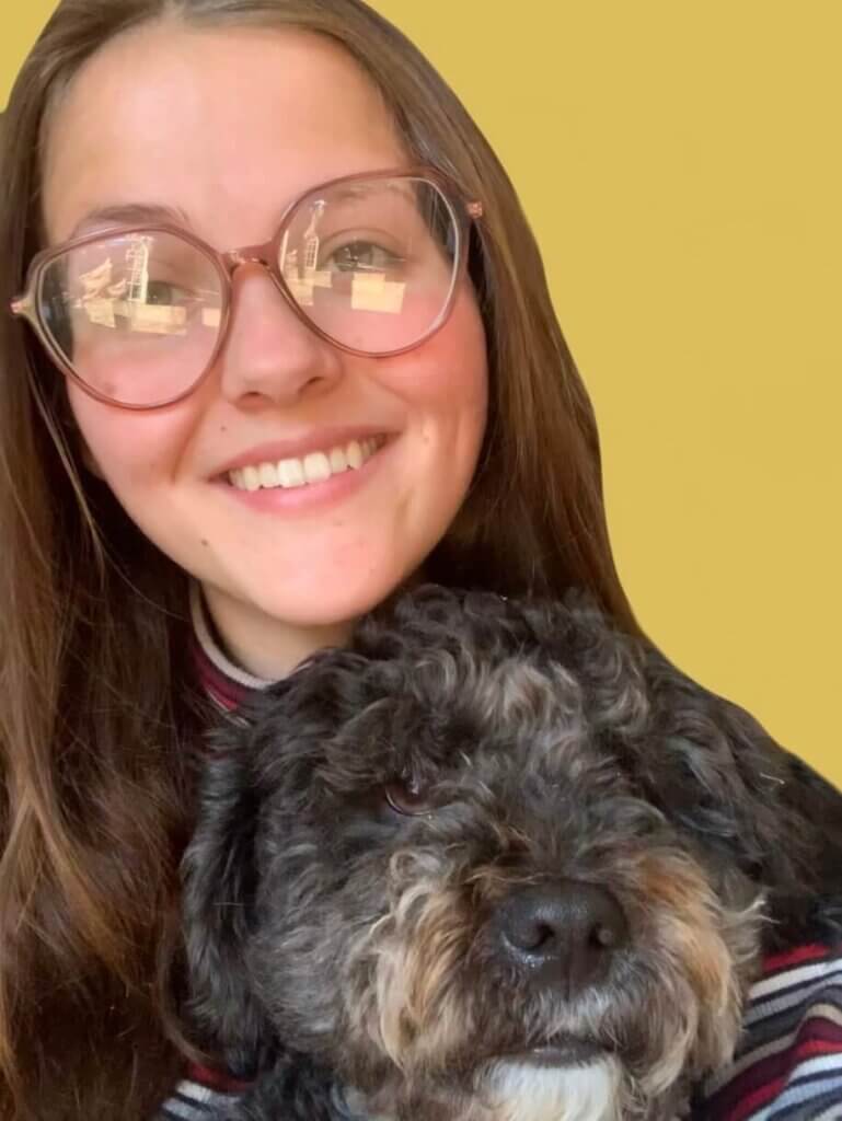 Photo of intern smiling to camera with adopted dog