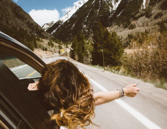 Woman leaning her hand out a window on a car ride