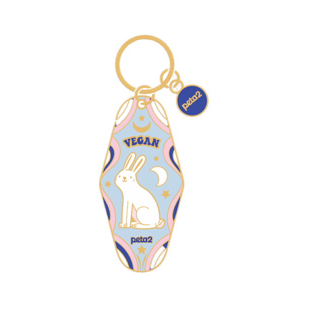 A gold motel keychain featuring an illustration of a rabbit, the moon, and stars. It reads "Vegan"